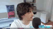 a man is talking into a microphone in front of a bed with a pillow with a man 's face on it