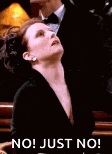 a woman in a black dress is sitting in a chair and looking up at something .