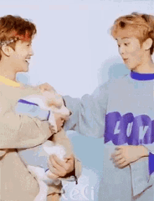 two young men are holding a small dog and one has a shirt that says ' l ' on the front