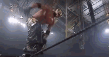 a wrestler is jumping over a rope during a match .