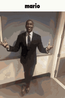 a man in a suit and tie is standing in a hallway with his arms outstretched and the word mario above him