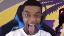 a young man is sitting in a chair with his tongue out .
