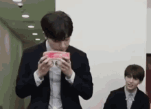 a man in a suit is eating a box of candy
