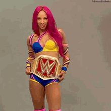 a woman with pink hair is holding a wrestling belt with a w on it