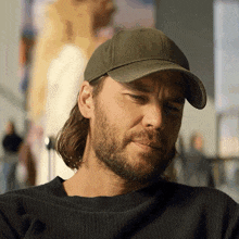 a man with long hair and a beard wearing a hat