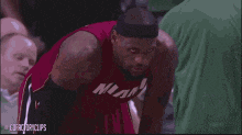 a basketball player wearing a red miami jersey is looking at the camera .