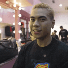 a young man wearing a black shirt with the letter g on it smiles