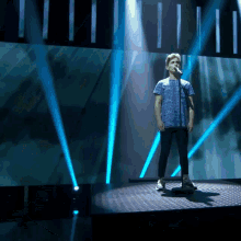 a man singing into a microphone on a stage with blue lights