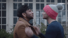 two men are standing next to each other and looking at each other .