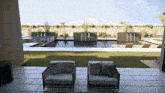 two chairs sit on a patio with a view of a swimming pool