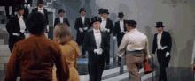 a group of men in tuxedos and top hats are walking down stairs