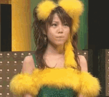 a woman in a green dress and yellow furry sleeves is making a funny face .