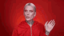 a man in a red sweater is making a face with his hands .