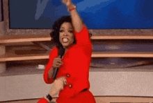 a woman in a red dress is holding a microphone and dancing