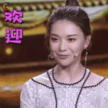 a woman wearing a white dress and earrings is smiling with chinese characters behind her .
