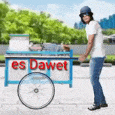 a man is standing next to a cart that says es dawet on it .