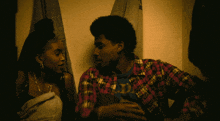 a man wearing a plaid shirt with the letter d on it sits next to a woman