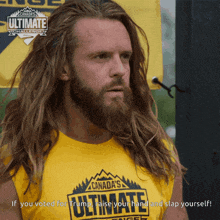 a man with long hair and a beard wears a canada 's ultimate challenge shirt