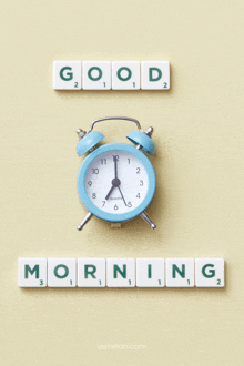 a blue alarm clock is surrounded by scrabble tiles that read good morning