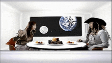 two people sitting at a table with plates of food in front of a screen with a picture of the earth on it