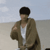 a man wearing a sweater and a white shirt is pointing up .