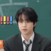 a boy in a suit and tie is standing in front of a blackboard that says new