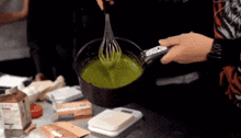 a person is whisking green liquid in a pot .
