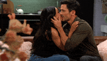 a man and woman kissing on a couch in a kitchen