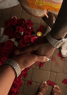 a man and woman holding hands in front of a bouquet of red roses .