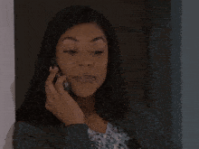 a woman talking on a cell phone while holding her hand up