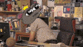 a man is sitting at a desk with a mouse head on his head