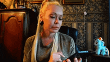 a woman with long blonde hair is sitting in a chair looking at her phone .