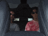 a man in a red tie dye shirt sits in the back seat of a car