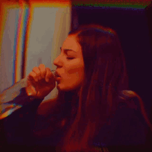 a woman is drinking from a glass with a rainbow colored background