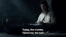 a man laying on the ground with the words " today the crumbs tomorrow the loaf "