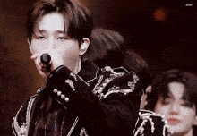 a young man is singing into a microphone with the name mark on the bottom of the image