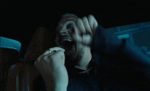 a man with a beard and earrings is screaming in a car