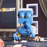 a blue robot is playing poker in front of a sign that says " collbit "