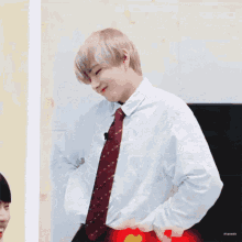 a young man in a white shirt and red tie is dancing .