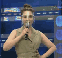 a woman wearing a face shield is holding a microphone and talking into it .