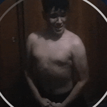 a shirtless man stands in a dark room