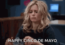 a woman is sitting in a chair and holding a piece of paper with the words `` happy cinco de mayo '' on it .