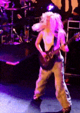 a woman playing a guitar on a stage with purple lights