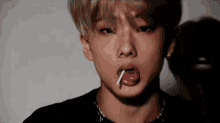 a young man is sticking his tongue out while eating a lollipop .