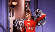 a cheerleader is wearing a red shirt with the word loser on it and holding pom poms .