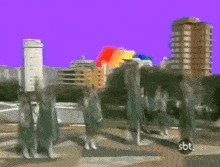 a group of people are dancing in front of a rainbow with sbt written on the bottom