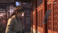 a man in a kimono stands in a hallway with chinese writing on the wall behind him