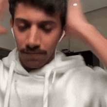 a man wearing headphones and a white hoodie is making a funny face