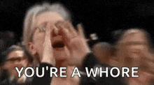 a woman is screaming in a crowd and saying `` you 're a whore '' in front of a crowd .