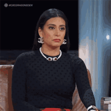 a woman wearing a pearl necklace and chanel earrings
